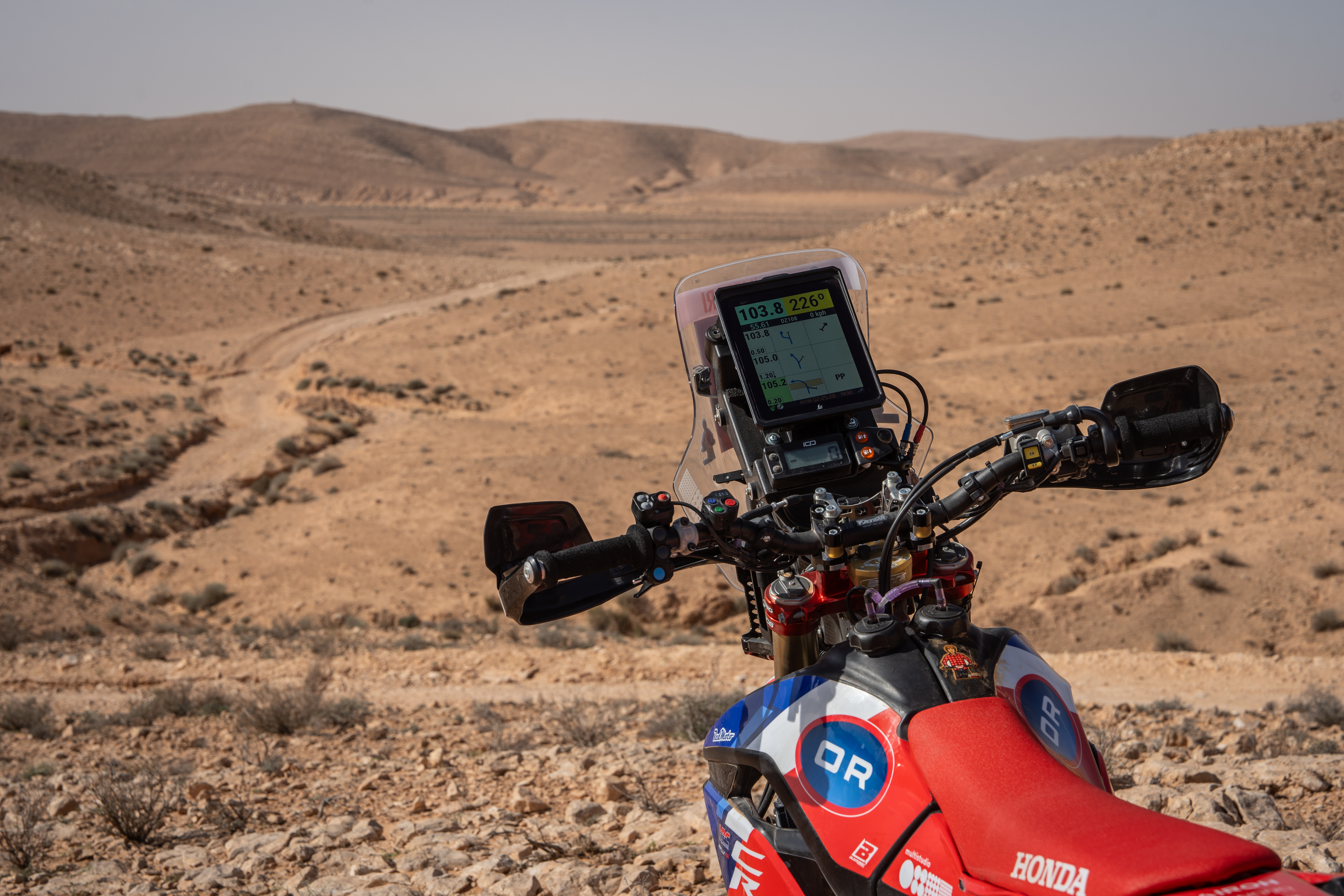 Rally motorcycle cockpit with the F2R Y1000 digital roadbook overlooking a desert valley during training